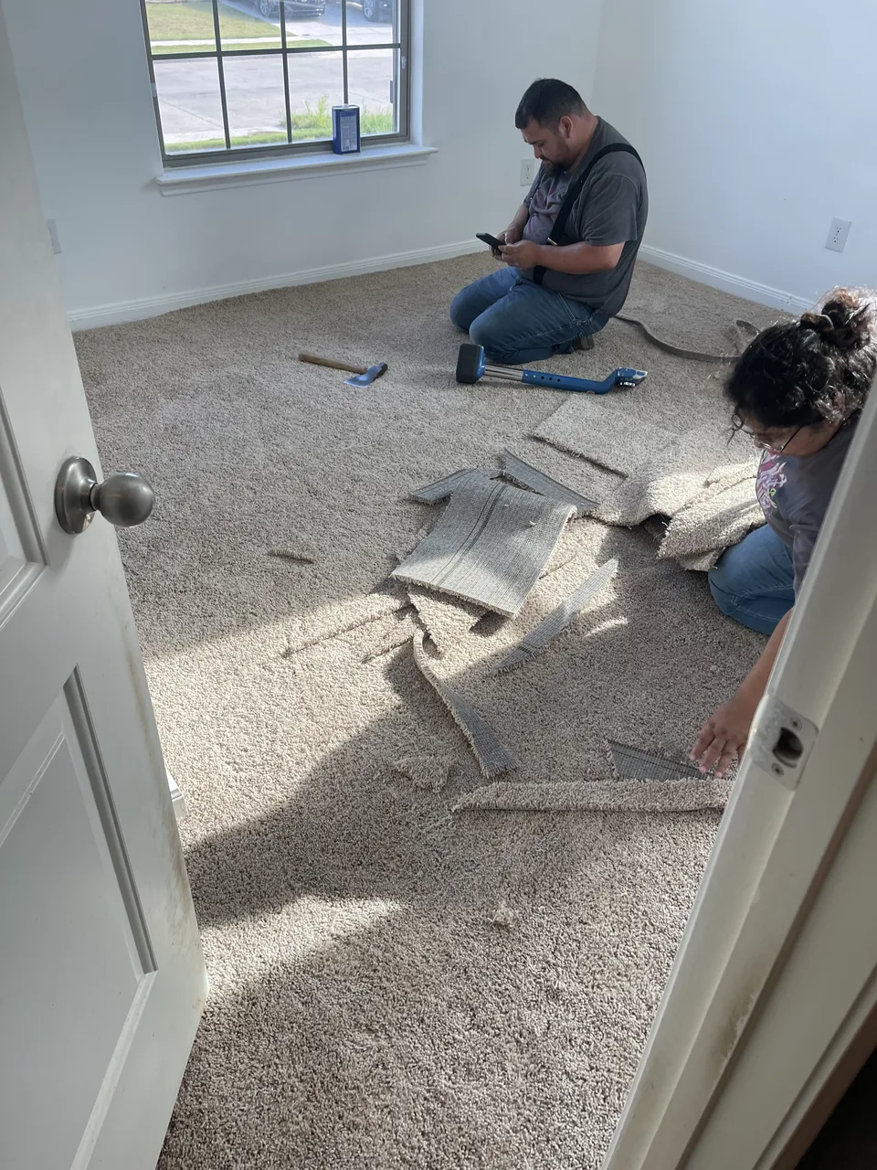 Workers removing carpet and pad from a residential room